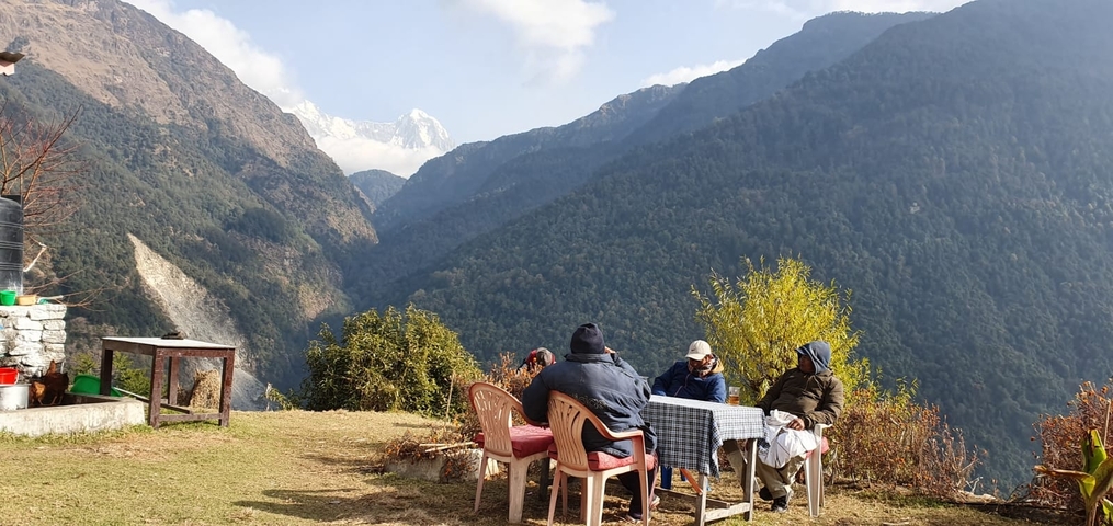       People sitting outdoors with mountains in the background.
  