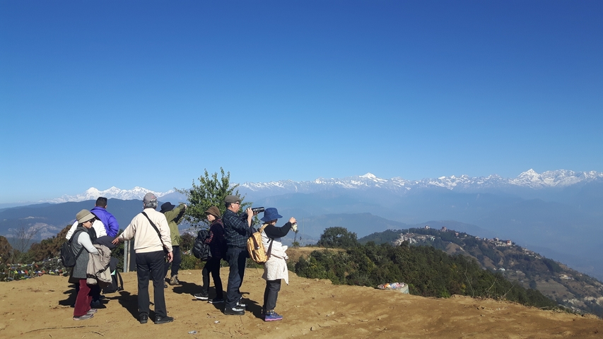 A group of tourists taking photos with mountain views.