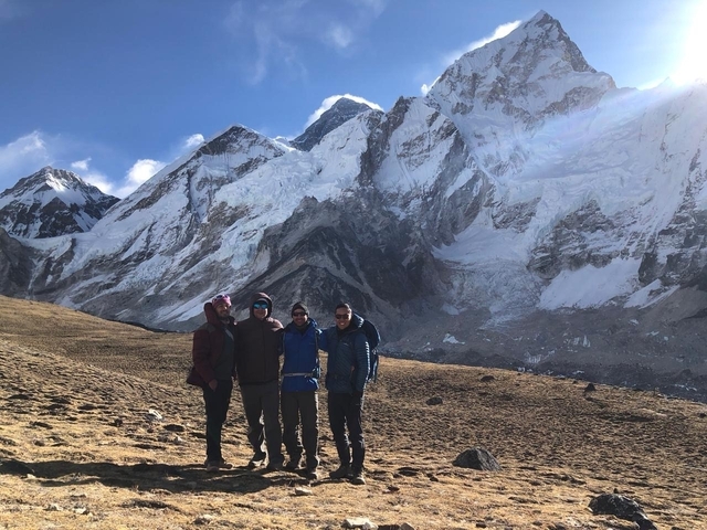 Group of people standing with snow-capped mountains in the background.