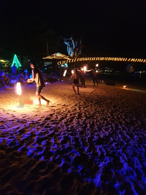A beach fire show with performers juggling flaming torches.
