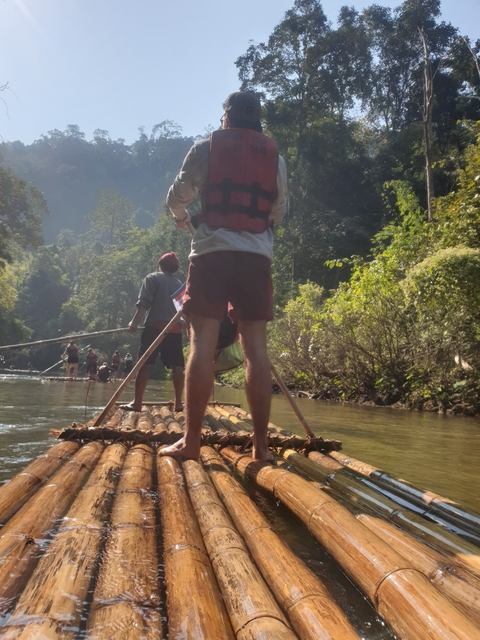 People rafting on a river surrounded by lush forest.