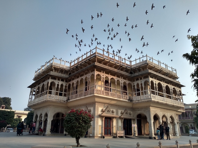 An ornately designed building with birds flying overhead.