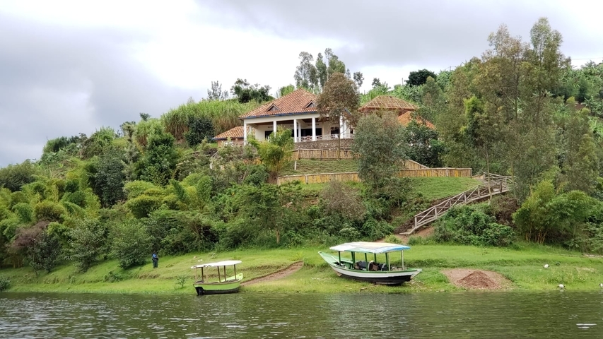       A house on a hill with boats by the lakeside.
  