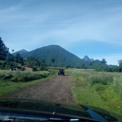       Mountain landscape with a dirt road and a vehicle.
  