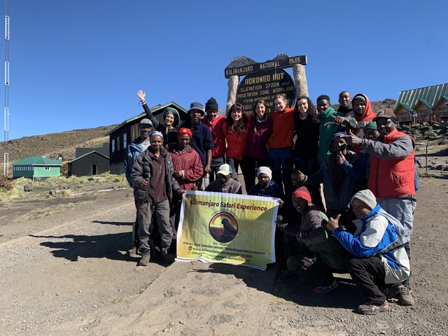 Group posing at Horombo Hut with informational signs.