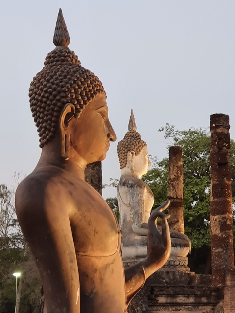 Statues of Buddha with ancient ruins in the background.