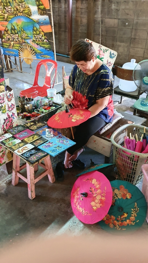       Artisan painting decorative umbrellas and fans.
  