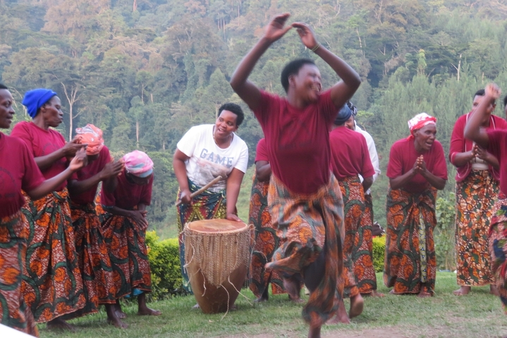 Group of people in traditional attire dancing and playing drums.