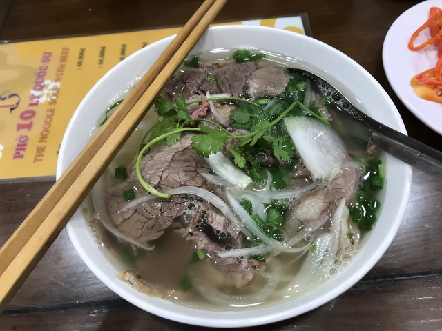       Bowl of pho with chopsticks resting on the bowl.
  