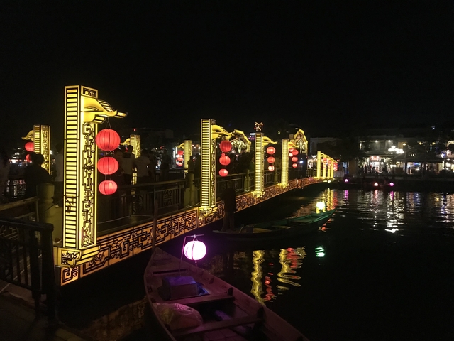       Bridge illuminated with lanterns at night, reflecting on water.
  