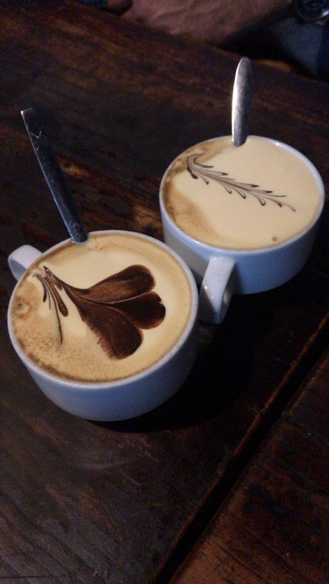       Two cups of coffee with latte art on top.
  