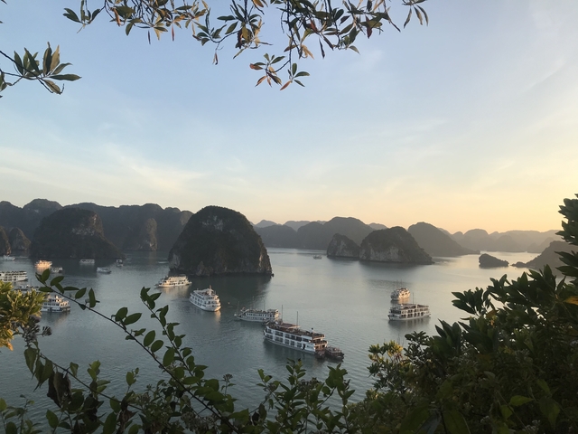       Halong Bay with boats and karst formations at sunset.
  