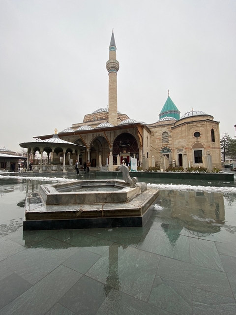       Ancient building with courtyard and fountain on a snowy day.
  