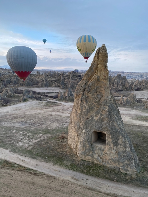       Hot air balloons floating over rocky terrain.
  