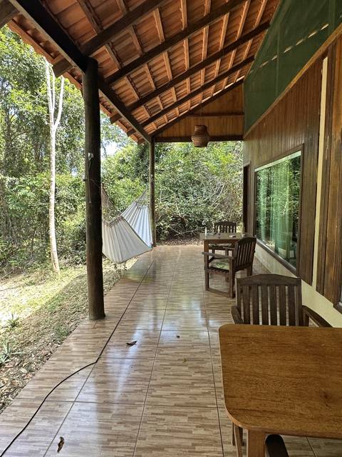       Exterior covered veranda with wooden furniture and hammock.
  