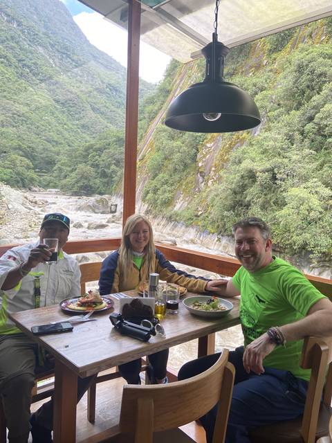 Group of people dining at a table near a river view.