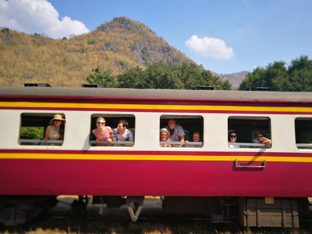       Group of people leaning out of a colorful train window.
  