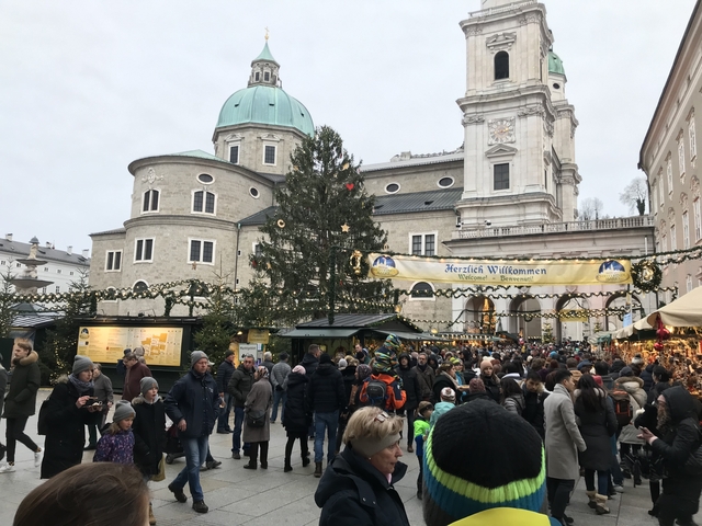       Busy Christmas market with decorations and a large building.
  