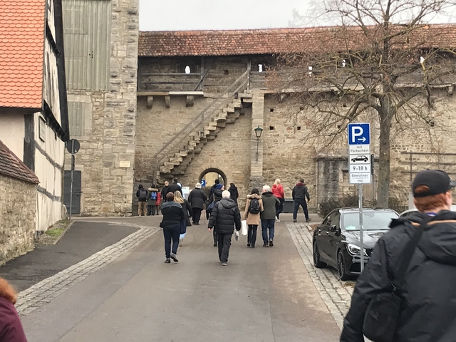 Group of people walking towards a historical stone gate.