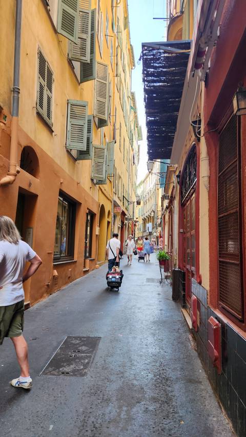       A narrow street lined with colorful buildings and window shutters.
  