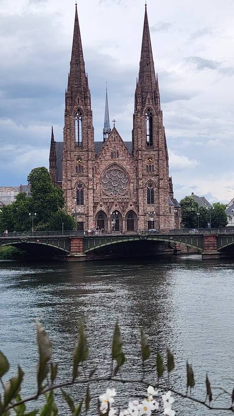       A large cathedral with twin spires reflected in a river.
  