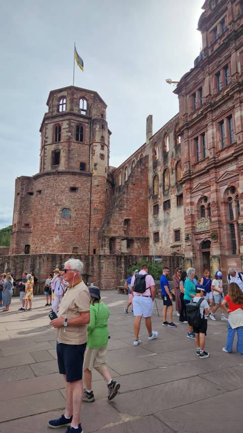      People walking near a historic building with towers.
  