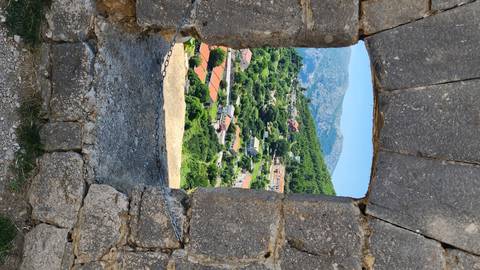       View through a fortification window showing a scenic landscape.
  