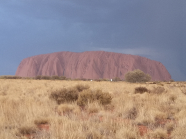 Blurry image of Uluru under a dark sky.