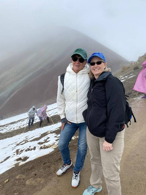 Two people posing with snowy mountain landscape in the background.