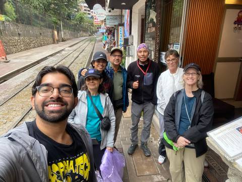       Group of people posing in a street with signs and shops around.
  
