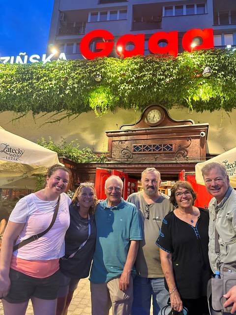 Group of people posing in front of a building with signage.
