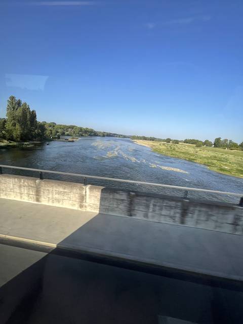       Riverscape with clear blue skies taken from a moving vehicle.
  