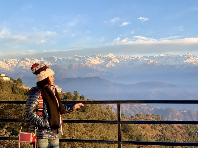 Person enjoying a mountain view with snow-covered peaks.