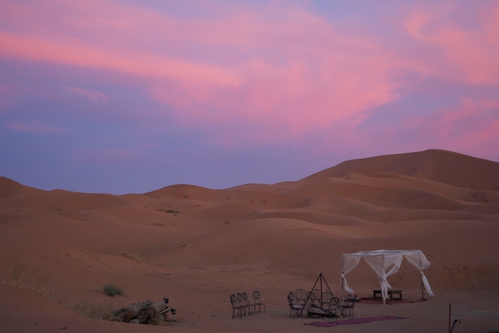 Desert landscape during a colorful sunset with a camp setup.