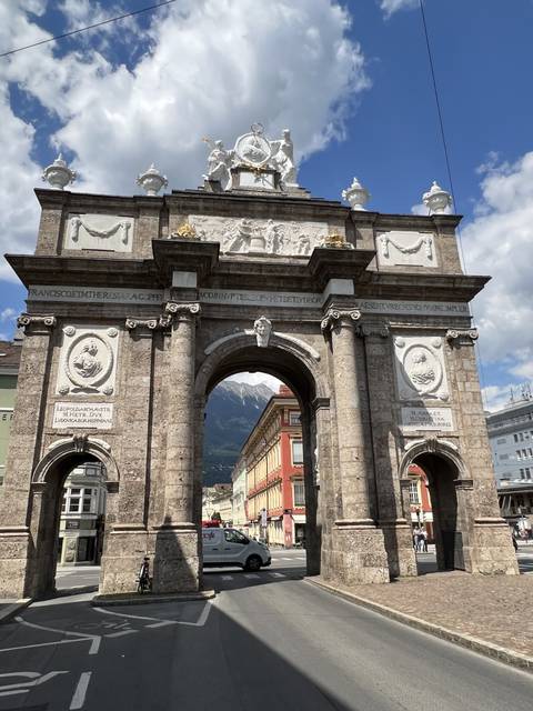       Triumphal arch in a city with historical sculptures.
  