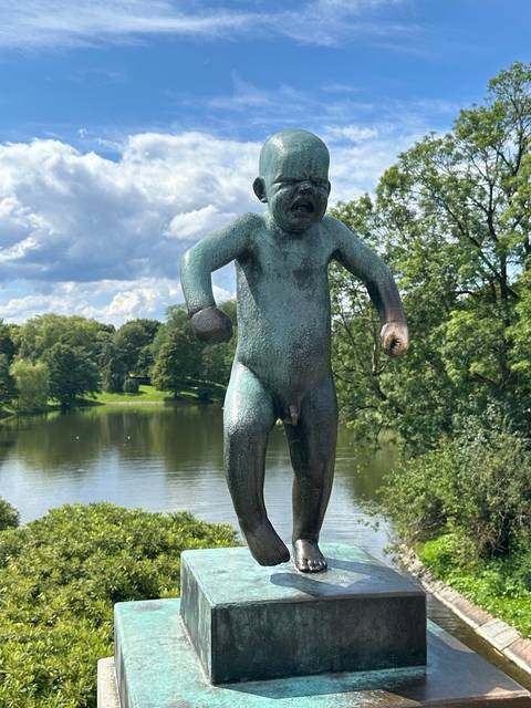 Statue of a young child in a park setting.