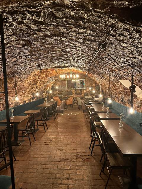       Underground restaurant or cafe with brick walls and chandeliers.
  