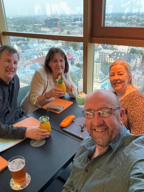 Group of people enjoying drinks at a high-rise with city views.