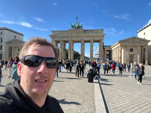 Person with sunglasses standing in front of a large stone gate.