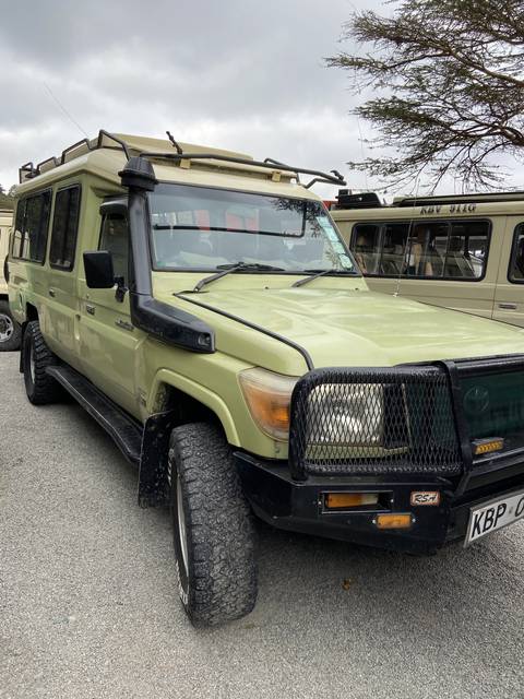 Safari vehicle parked on a dirt road.