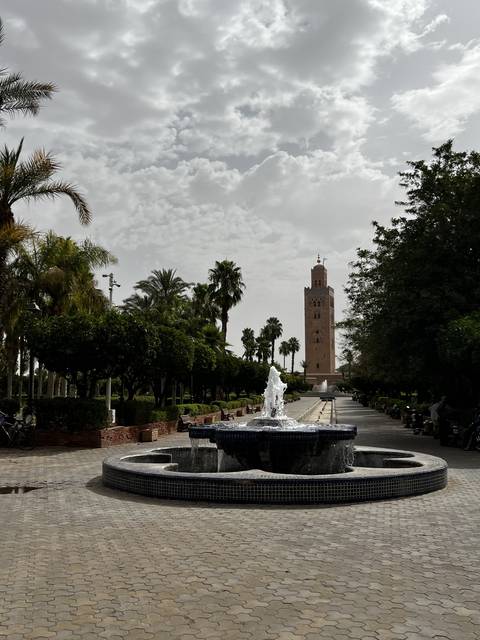 A fountain with a historical building in the background.
