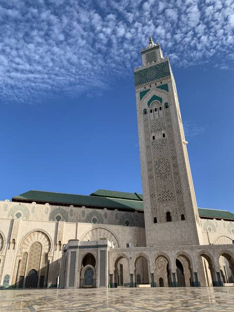       Tall minaret of a mosque reaching into a clear blue sky.
  