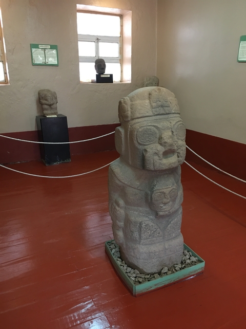       Stone statues showcased in a museum with ropes around them.
  