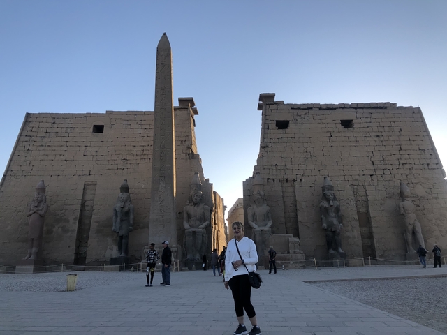 Person standing in front of ancient Egyptian temple with statues.
