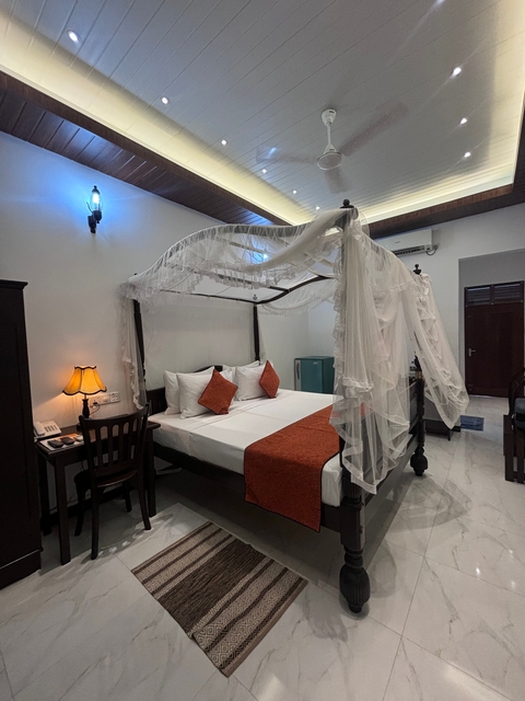       Bedroom in a hotel with a canopy bed and warm lighting.
  