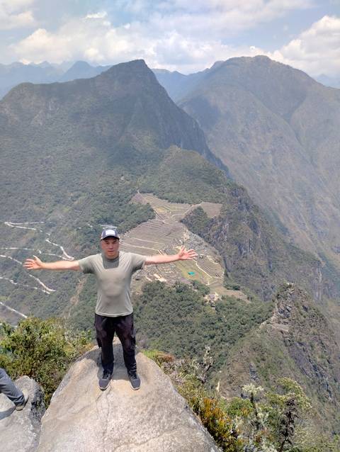 A person with arms outstretched, overlooking a mountain vista.