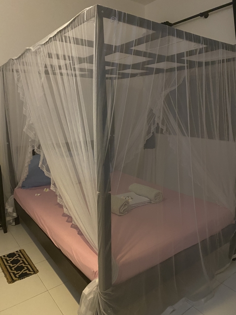       Interior of a room with a canopy bed and rolled towels.
  