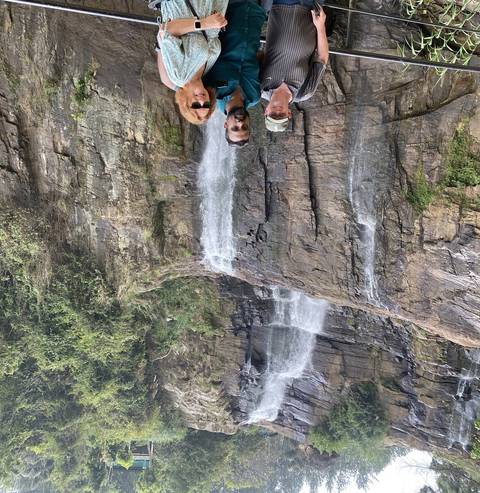       Three people standing at a viewpoint near a waterfall.
  