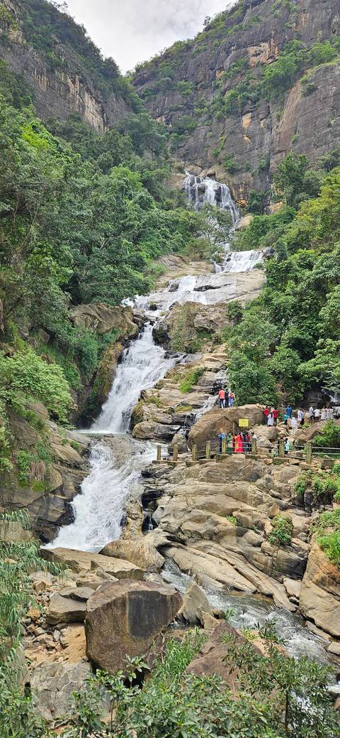       Waterfall surrounded by trees with people observing.
  