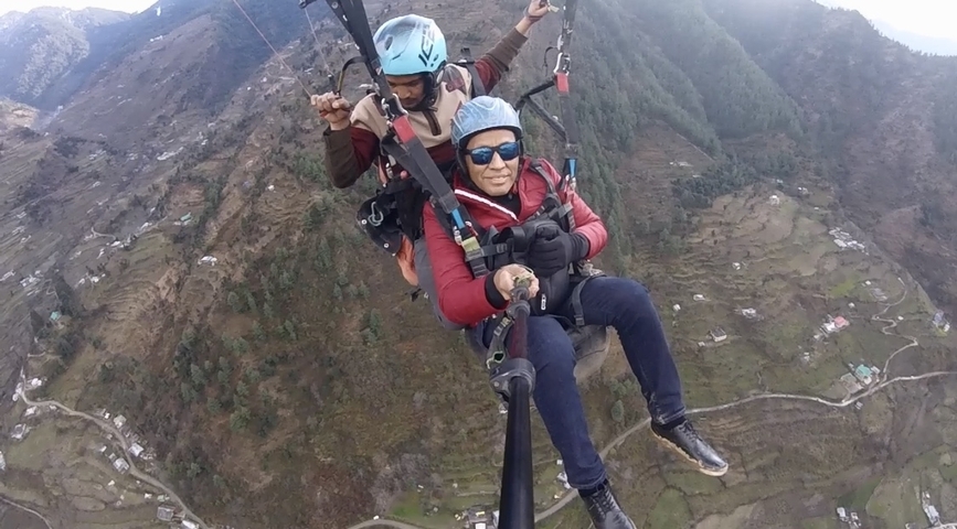 Two people paragliding over a mountainous landscape.
